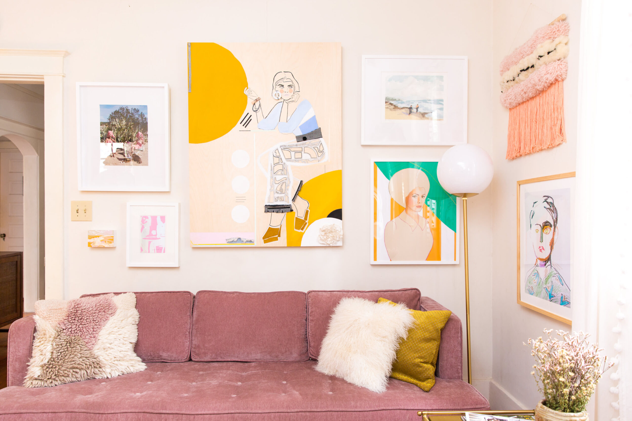 Розовый диван в углу комнаты и картины на стене
